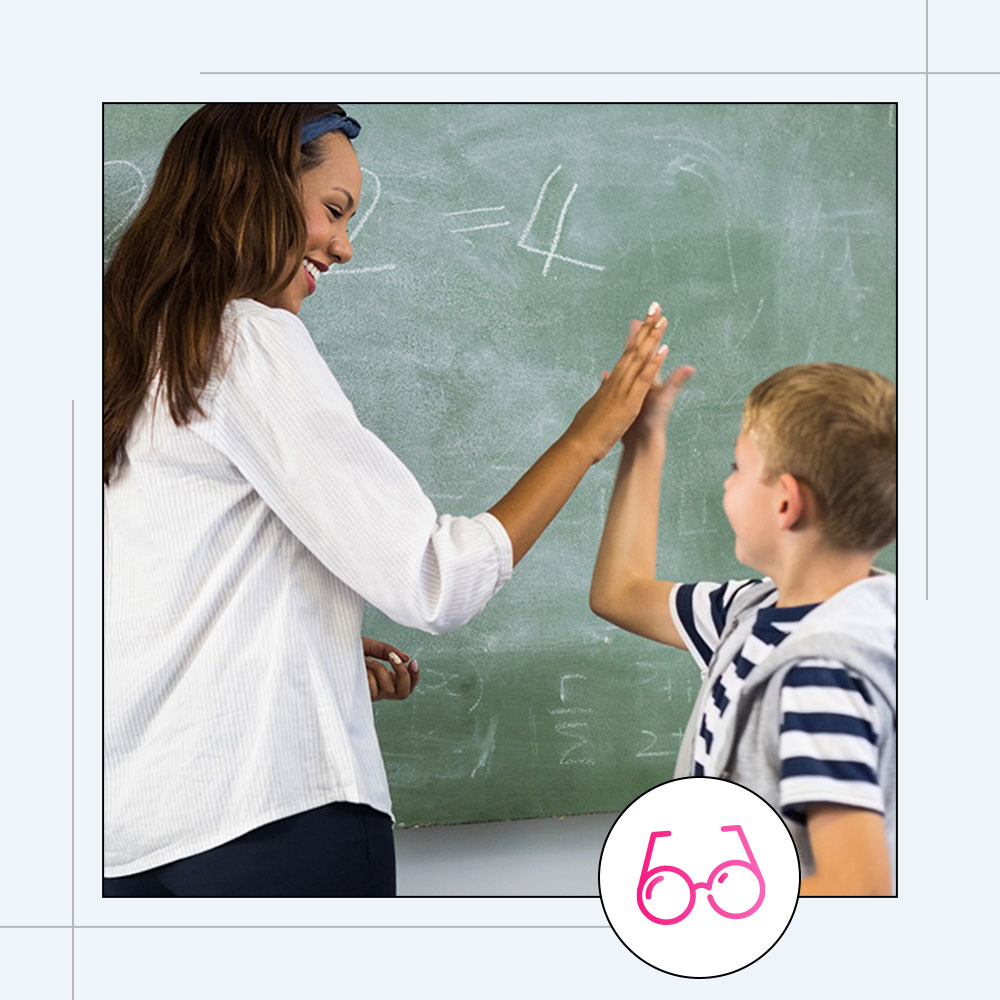 A teacher giving her student a high five in front of a blackboard