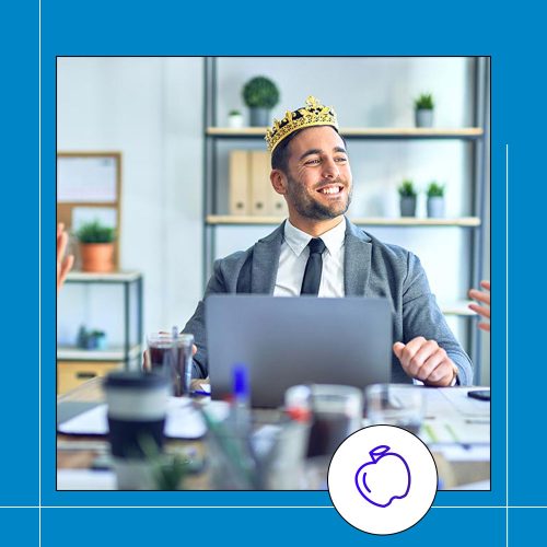 a man sitting in front of a laptop smiling wearing a crown