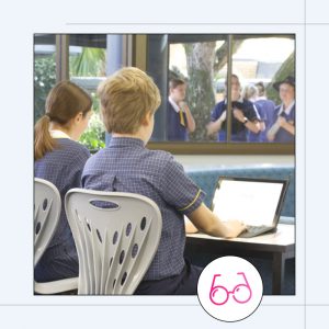 students sitting at a desk on computers