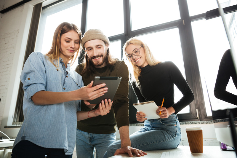 young colleagues standing office using tablet computer